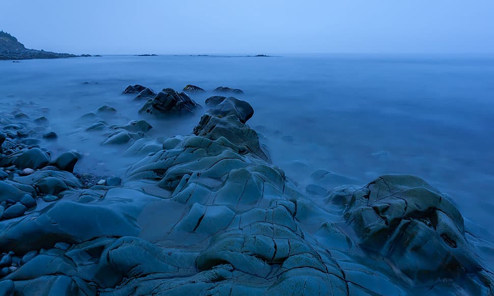 coastal water and rocks at dusk blue hour