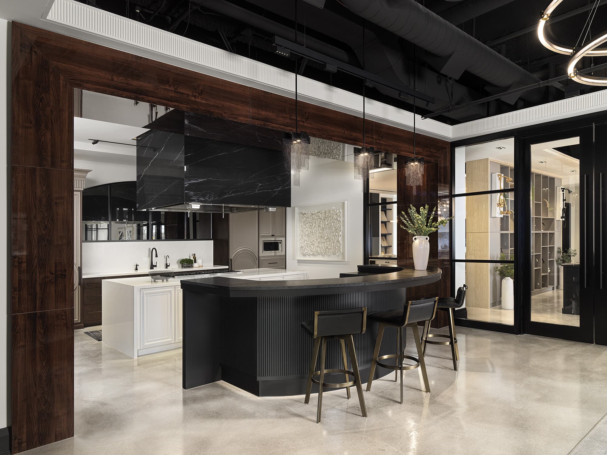 Commercial-grade kitchen and bar area at Primont XC with marble hood, gas range, integrated appliances, and curved seating counter