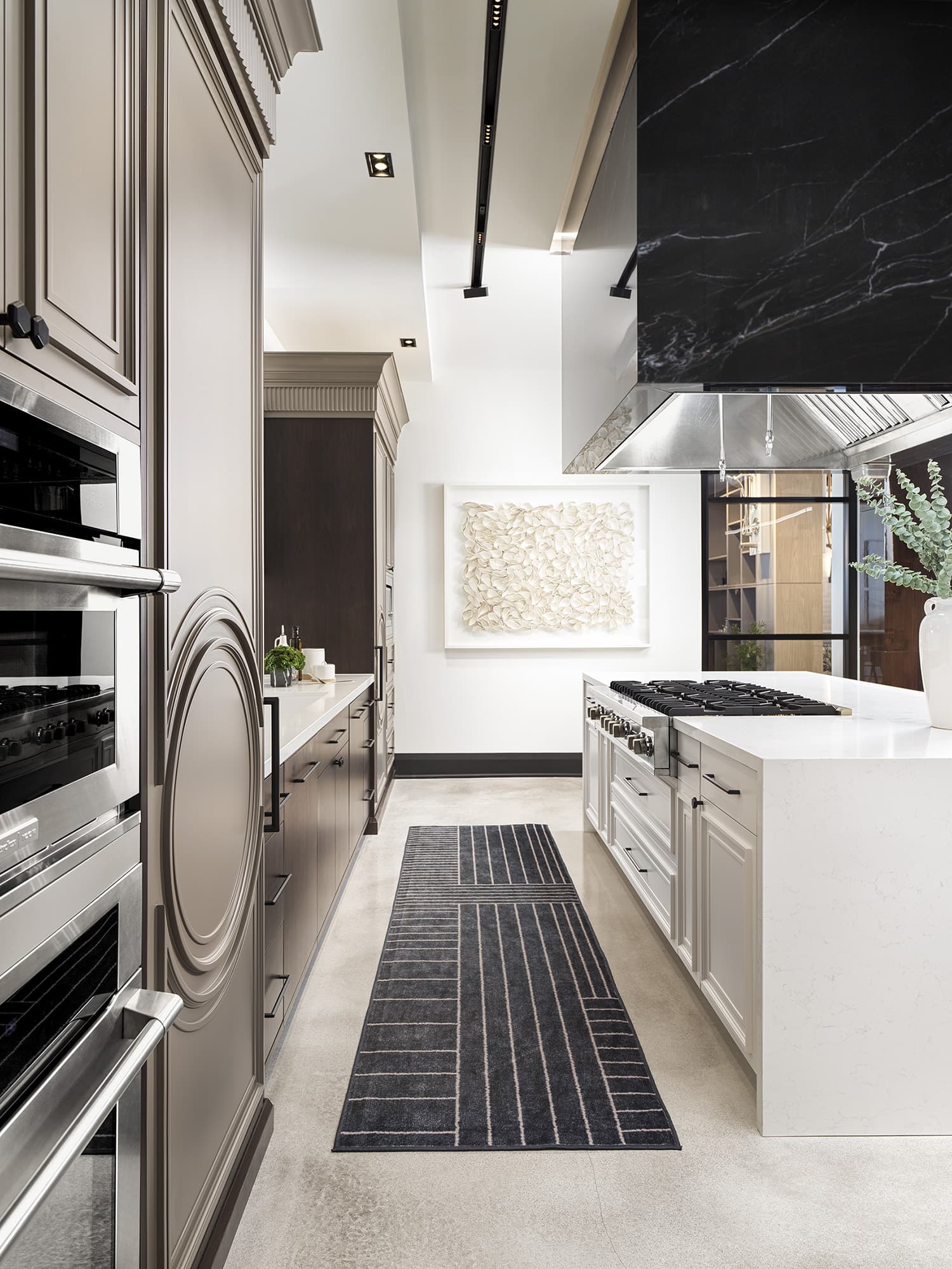 Side view of commercial gas range and black marble hood at Primont XC with custom cabinetry and integrated appliances