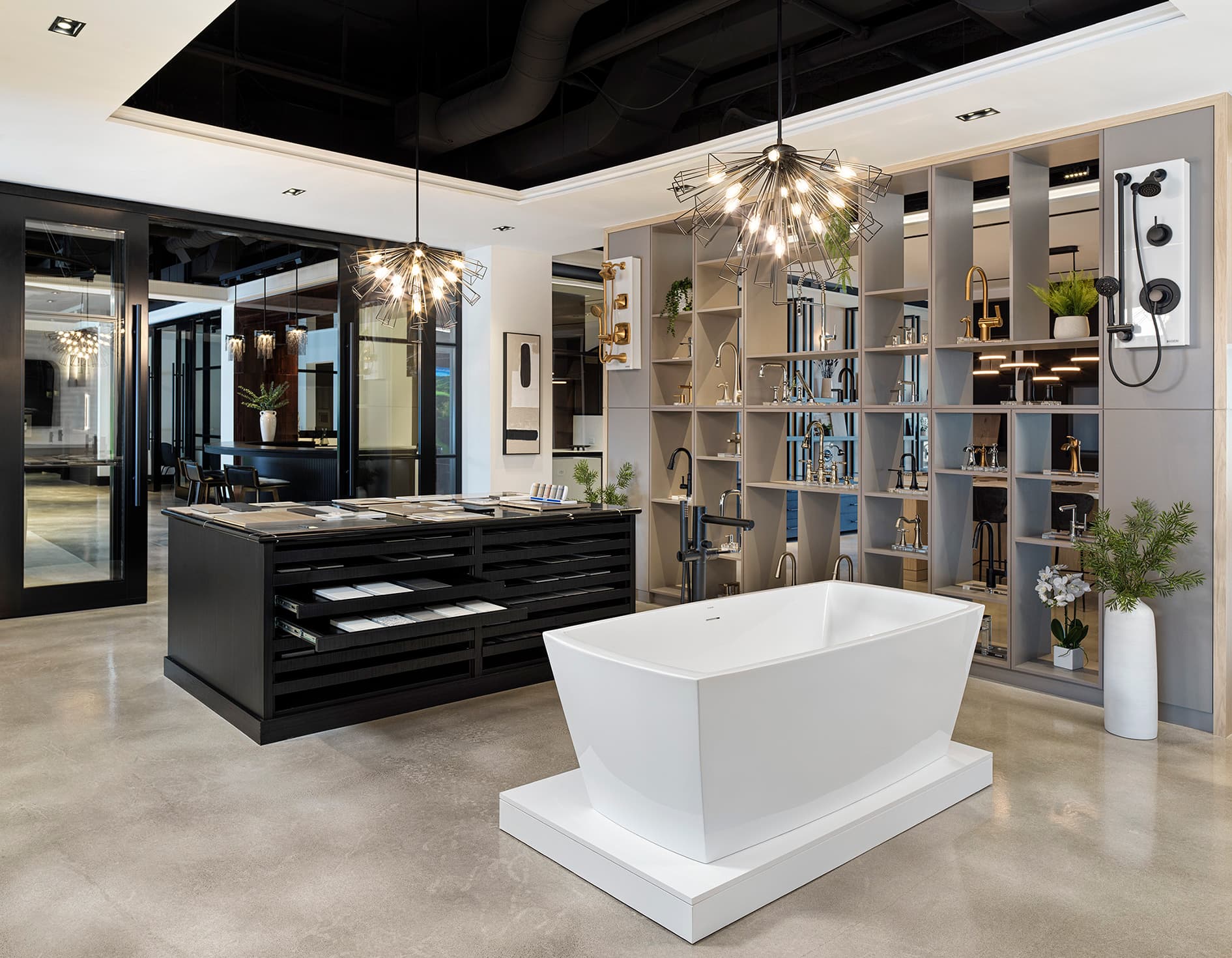 Modern bathroom fixture display with freestanding tub, sample drawers, and geometric pendant lights at the Primont Experience Centre décor studio