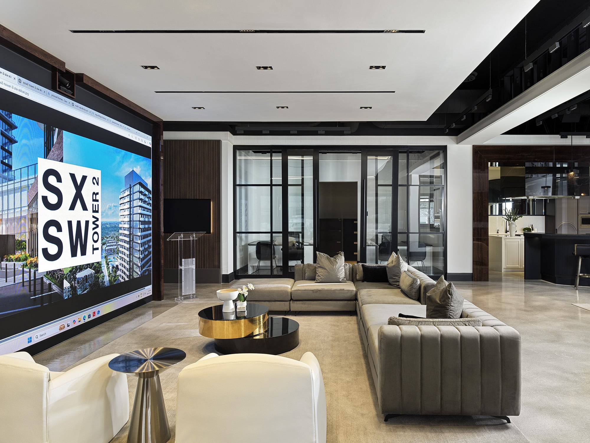 Presentation lounge at Primont XC featuring a large digital media wall, sectional seating, and glass-walled meeting rooms