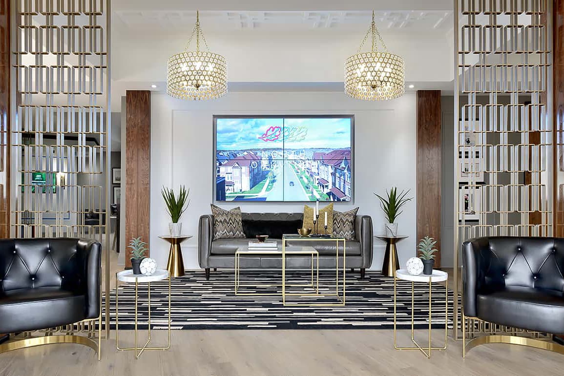 Upscale presentation centre interior featuring gold geometric room dividers, crystal chandeliers, and a luxury lounge area with a large digital community display.