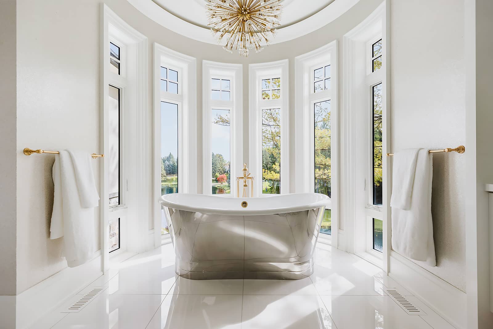 luxury bathroom with reflective soaker bath and gold hardware