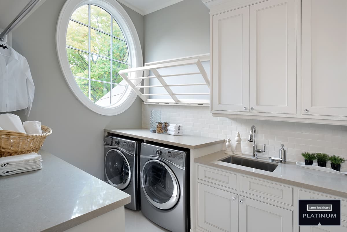 White laundry drying rack in down position with grey washer, dryer, sink, countertop