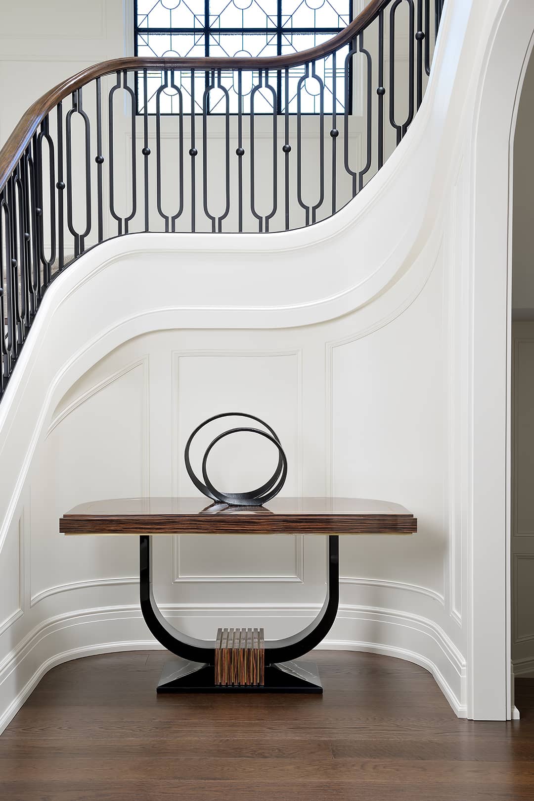 luxury foyer with wood console table and curved staircase