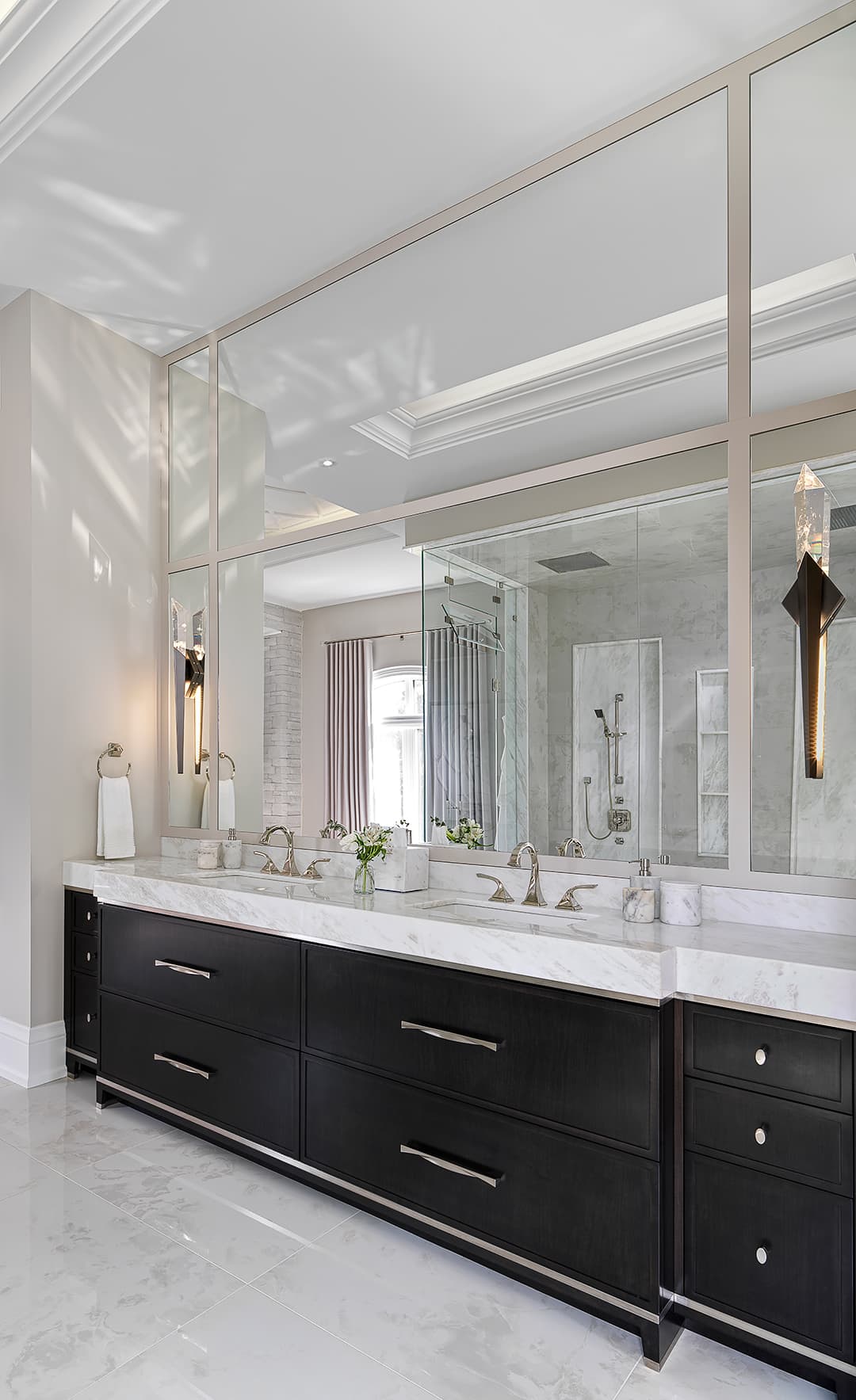 Luxury bathroom design by Jane Lockhart featuring a double vanity with dark wood cabinetry, marble countertop, and elegant wall sconces.