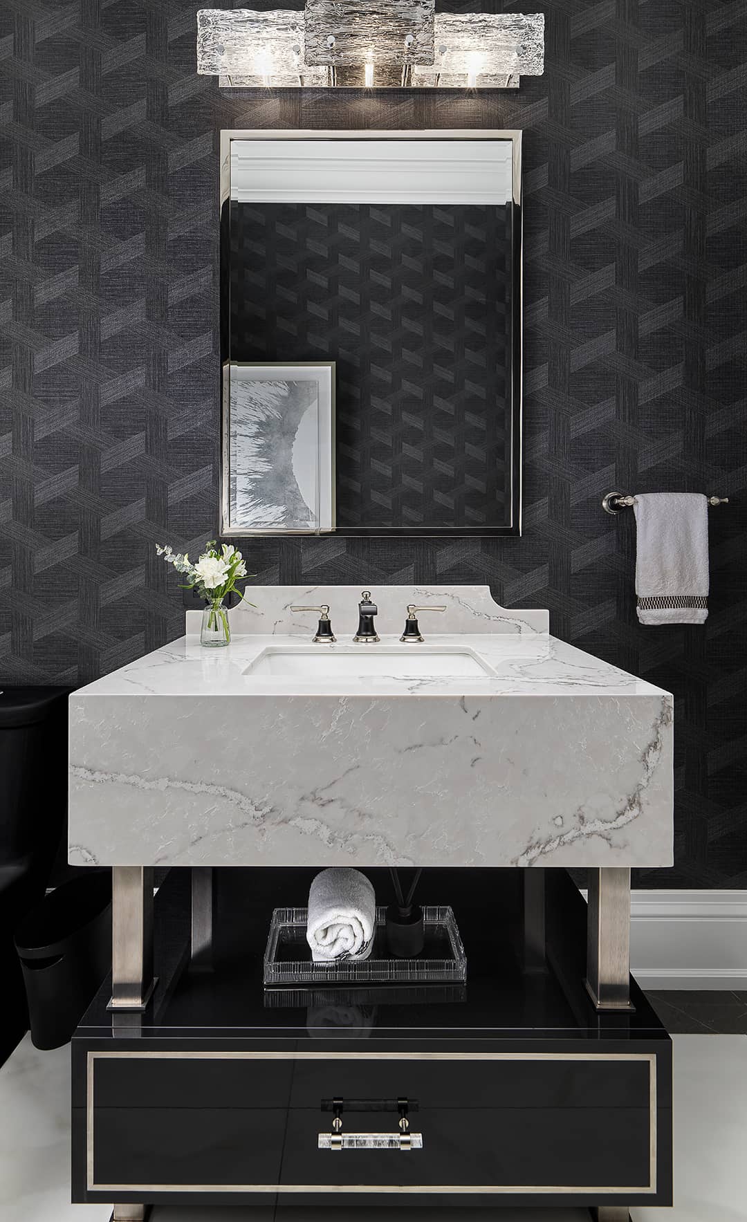 Modern powder room with black geometric wallpaper, marble vanity, chrome fixtures, and elegant crystal light fixture.