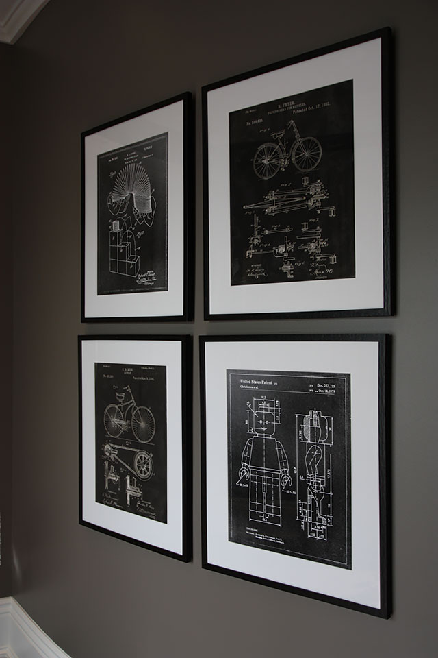 Group of 4 black and white prints of framed blueprints on gray wall.