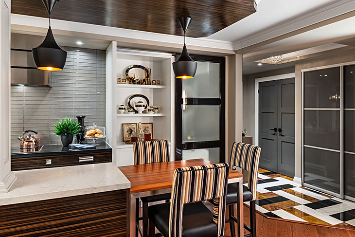 Contemporary kitchen nook with striped chairs, modern pendant lighting, built-in shelving, and a bold black-and-white patterned floor in the entryway