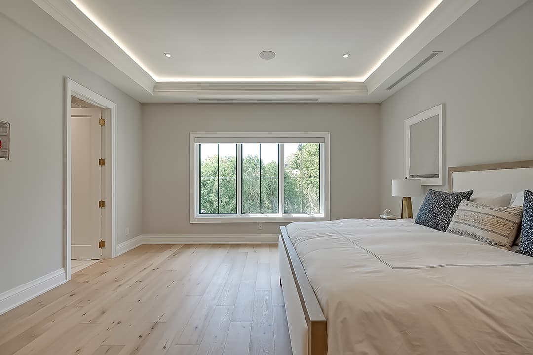 primary bedroom with light wood floors, neutral bedding, large window views, and recessed ceiling lighting