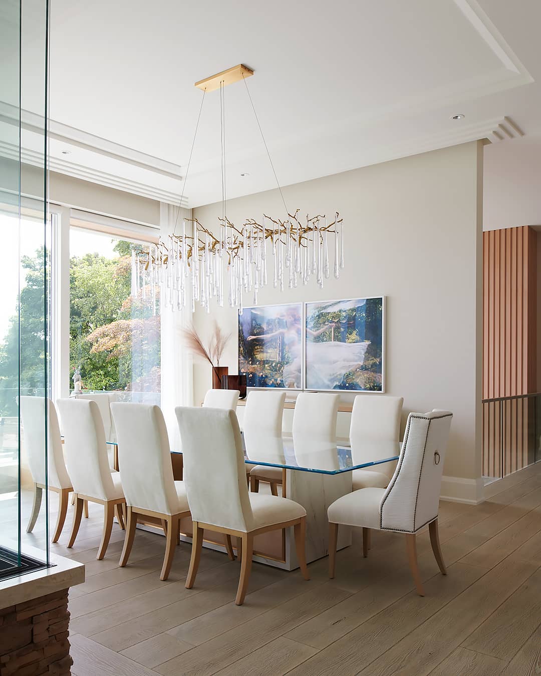 large dining table with 10 white chairs and modern chandelier