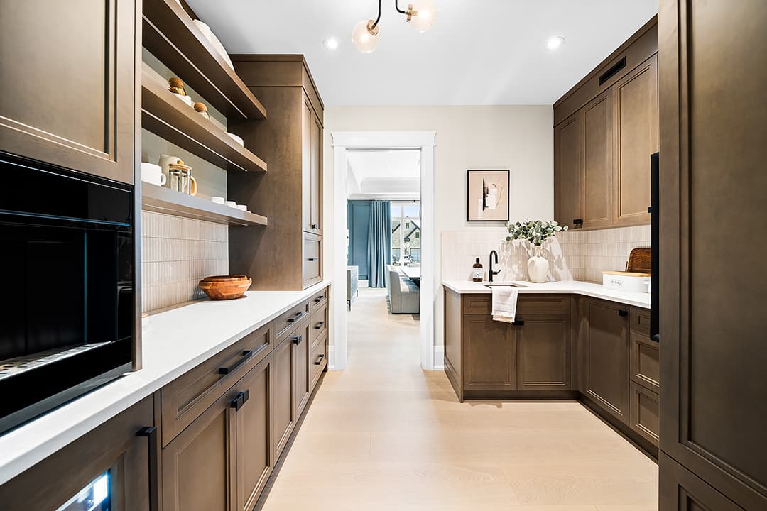 Working pantry with custom wood cabinetry, open shelving, integrated appliances, and a secondary sink designed for food prep and entertaining.